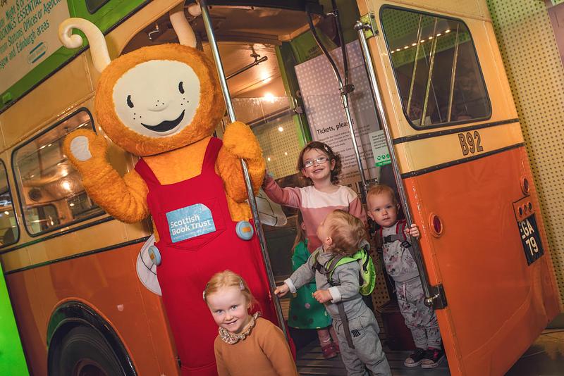 Bookbug and children waving from a bus.